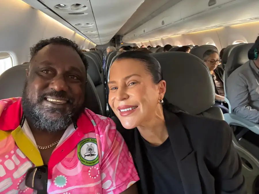 Edmund Tamwoy in a pink Crystal Ailan polo shirt, seated on a flight beside a colleague while travelling for the business.